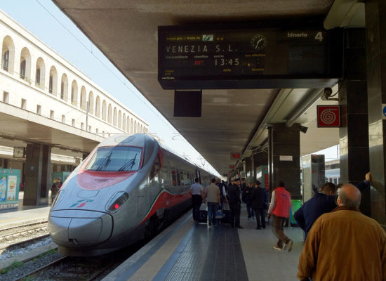 The picture shows a train on a track at Venice Train Station. From this page you can Book a private transfer from Venice Train Station to your hotel